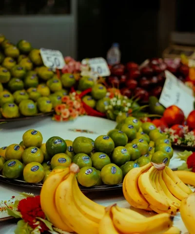 A colorful display of fresh fruits including bananas and limes at a bustling market.