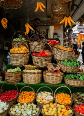 A vibrant display of fresh fruits and vegetables in wicker baskets at an outdoor market.