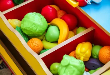 Vibrant display of toy fruits and vegetables in a wooden drawer, offering playful learning for children.